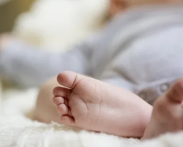 Acercamiento de los pies de un bebé acostado sobre una superficie suave.